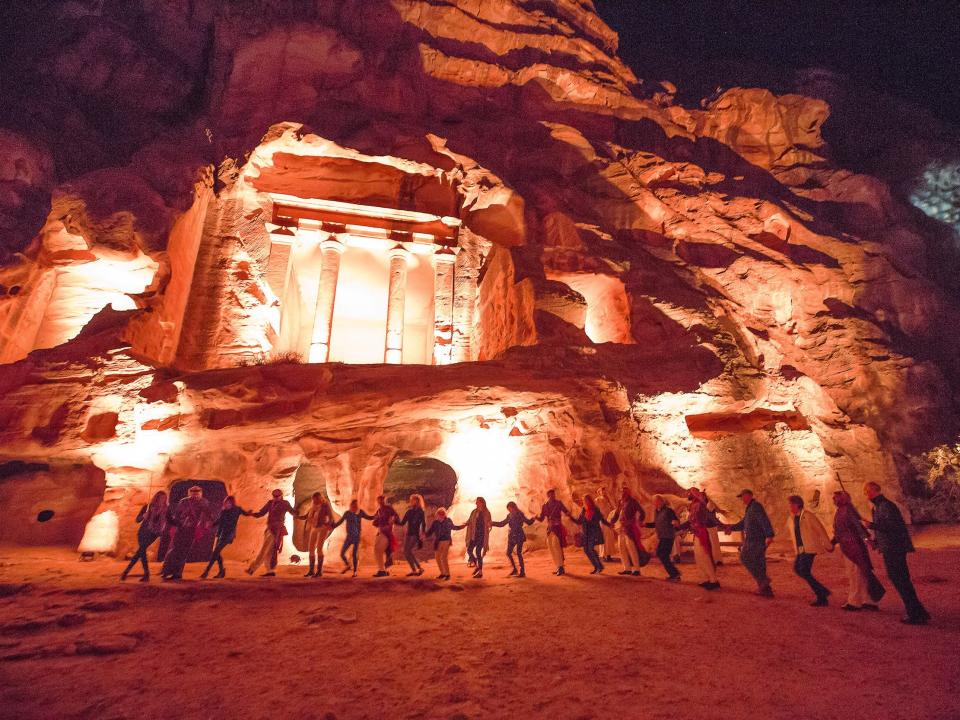 Petra, Jordan at night with people holding hands in a line in front of the site.