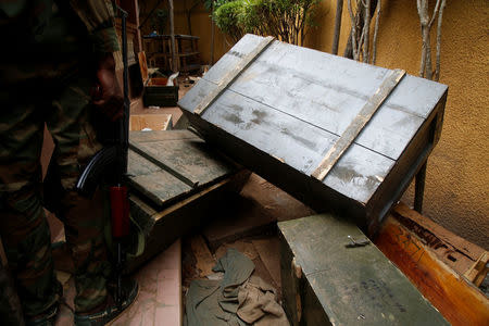 A mutinying soldier stands next to a box of weapons found after investigation at a residence of a civilian in Bouake, Ivory Coast, May 15, 2017. REUTERS/Luc Gnago