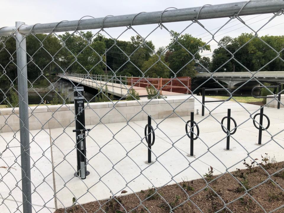A fence closes off the nearly finished plaza and the unfinished pedestrian bridge over the St. Joseph River on South Bend's Coal Line Trail in September 2023.
