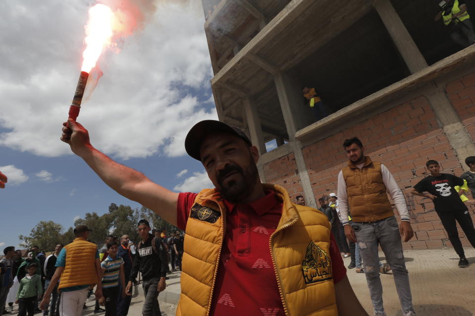 A demonstrator lights a flare during a protest in Bordj Bou Arreridj, east of Algiers, Friday, April 26, 2019. Algerians are massing for a 10th week of protests against their country's ruling class, calling for the ex-president's brother to be put on trial. (AP Photo/Toufik Doudou)