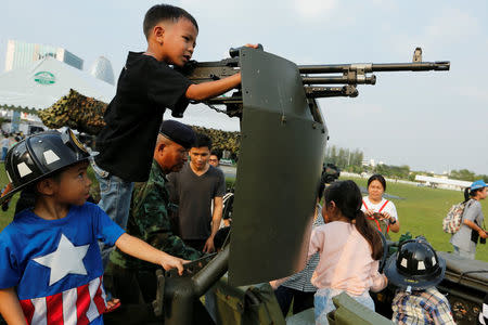 Children play with a weapon on the top of an army vehicle during Children's Day celebration at a military facility in Bangkok, Thailand January 14, 2017. REUTERS/Jorge Silva