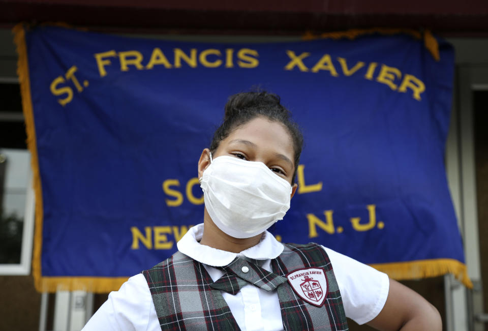 Miranda Gonzalez, 9, a former third grade student at St. Francis Xavier School, poses for a portrait in front of the building Thursday, Aug. 6, 2020, in Newark. The Archdiocese of Newark announced the school's closure just four weeks before the new academic year. "I'm very disappointed and very sad," said Miranda's mother, Wanda Gonzalez. "The area needs a Catholic school." (AP Photo/Jessie Wardarski)