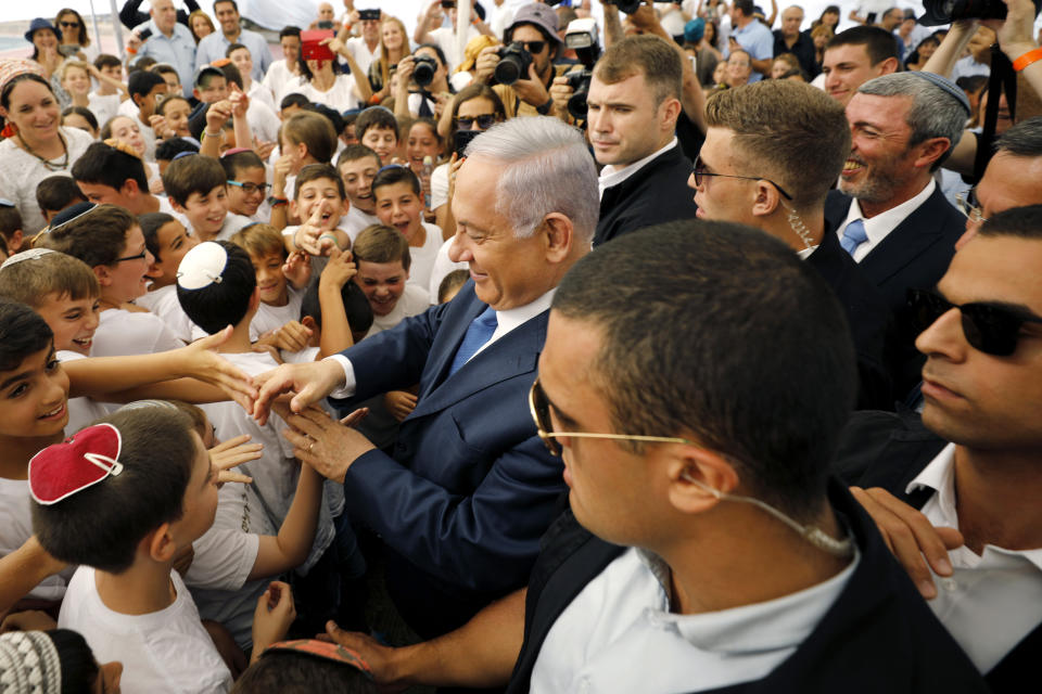 Israeli Prime Minister Benjamin Netanyahu, center, greets students during a ceremony opening the school year in the settlement of Elkana Sunday, Sept. 1, 2019. Netanyahu is reaffirming his pledge to impose Israeli sovereignty on West Bank settlements. (Amir Cohen/Pool Photo via AP)