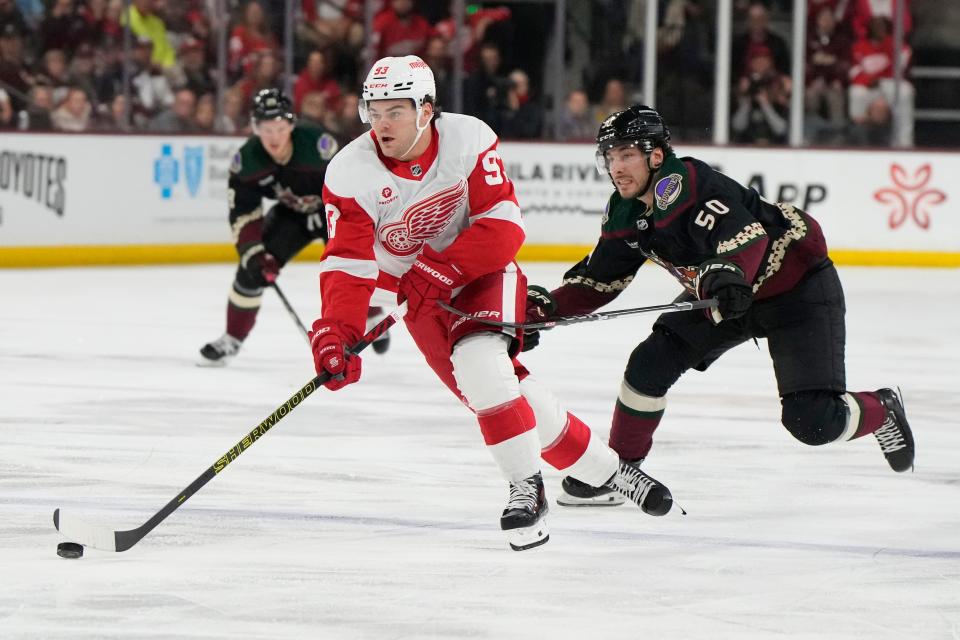 Detroit Red Wings right wing Alex DeBrincat carries the puck in front of Arizona Coyotes defenseman Sean Durzi (50) in the second period at Mullett Arena in Tempe, Arizona, on Friday, March 8, 2024.