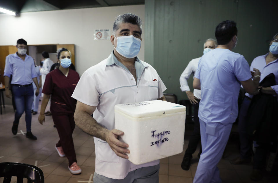 El enfermero Gustavo Rodríguez lleva una hielera de la vacuna rusa Sputnik V para el COVID-19 que administrará a sus compañeros trabajadores de la salud en el Hospital Dr. Pedro Fiorito en Avellaneda, Argentina, el martes 29 de diciembre de 2020. (AP Foto/Natacha Pisarenko)