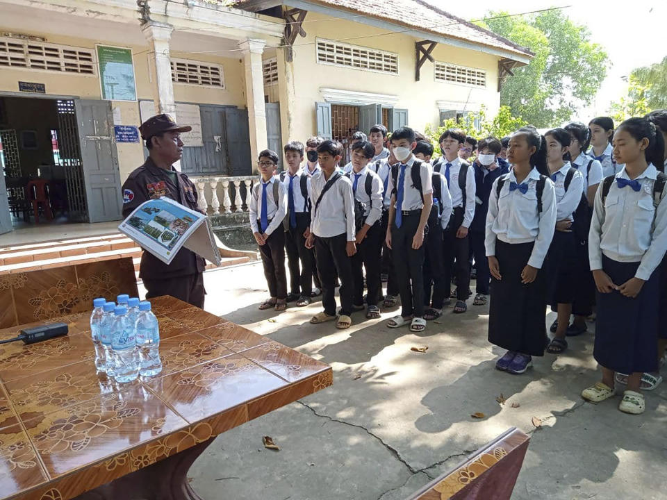 In this photo released by the Cambodia Mine Action Center, CMAC, a deminer expert, left, explains students at Queen Kosamak High School in Kratie Province, northeastern of Phnom Penh, Cambodia Sunday, Aug. 13, 2023. Cambodian authorities have temporarily closed the high school where thousands of pieces of unexploded ordinance from the country's nearly three decades of civil war have been unearthed. (Cambodia Mine Action Center via AP)