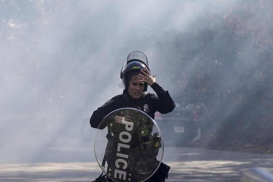 A police officer runs out of a cloud of gas during a demonstration in opposition to a new police training center, Monday, Nov. 13, 2023, in Atlanta. (AP Photo/Mike Stewart)