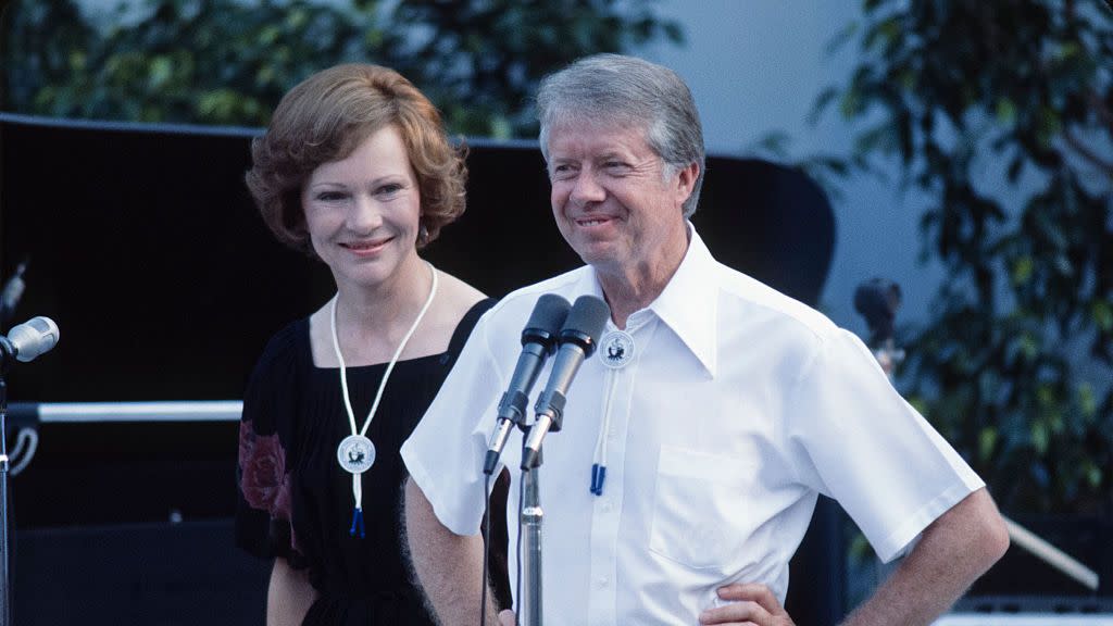 president jimmy carter and wife rosalynn carter smiling together onstage at a festival