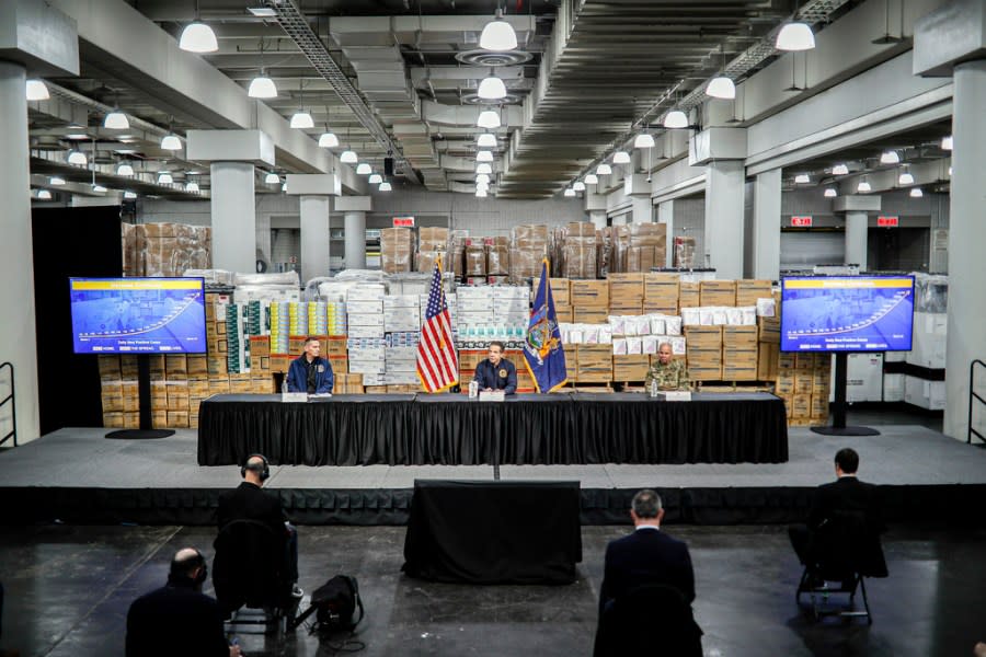 FILE – New York Gov. Andrew Cuomo, center, speaks while practicing social distancing against a backdrop of medical supplies during a news conference at the Jacob Javits Center that will house a temporary hospital in response to the COVID-19 outbreak, Tuesday, March 24, 2020, in New York. Some states that stockpiled millions of masks and other personal protective equipment during the coronavirus pandemic are now throwing the items away. (AP Photo/John Minchillo, File)