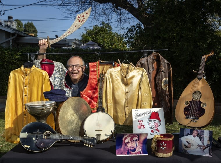 NORTHRIDGE, CA - FEBRUARY 10, 2021: Arshag Chookoorian is photographed at his home in Northridge with memorabilia that belonged to his dad, Armenian musician, actor, and belly-dance bandleader Guy Chookoorian, who entertained for over 60 years. Instruments his dad played include a mandolin, left, a banjo, center, and an oud, right. He is holding a decorative sword that was a prop, used by the belly dancers during his dad's shows at the Flamingo Hotel in Las Vegas back in 1963. Guy Chookoorian passed away on January 31, 2021 at the age of 97. (Mel Melcon / Los Angeles Times)