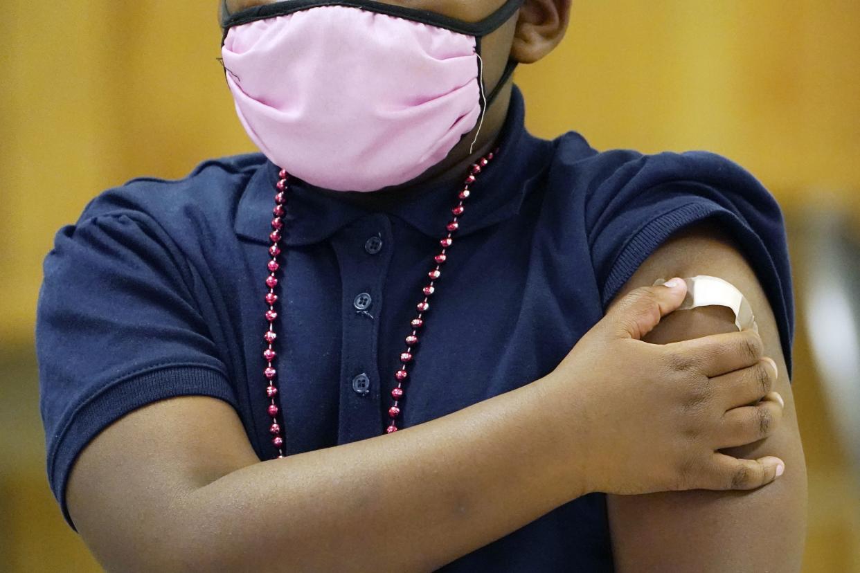 A student receives a bandage on the arm after receiving a children's dose of the Pfizer COVID-19 vaccine from a nurse in Jackson, Miss., on Feb. 16, 2022. 