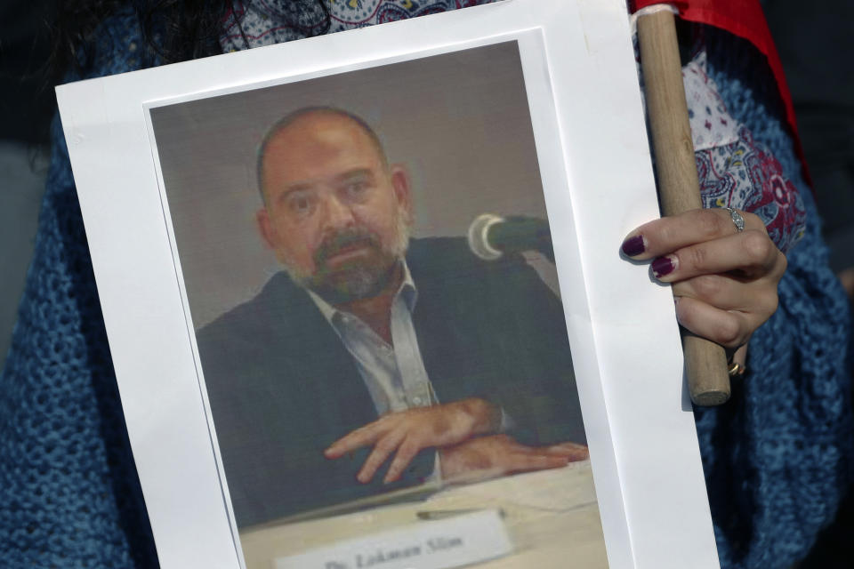 An anti-Hezbollah protester holds a picture of Lokman Slim, a longtime Shiite political activist and researcher, who has been found dead in his car, during a protest in front of the Justice Palace in BeirutBeirut, Lebanon, Thursday, Feb. 4, 2021. (AP Photo/Bilal Hussein)