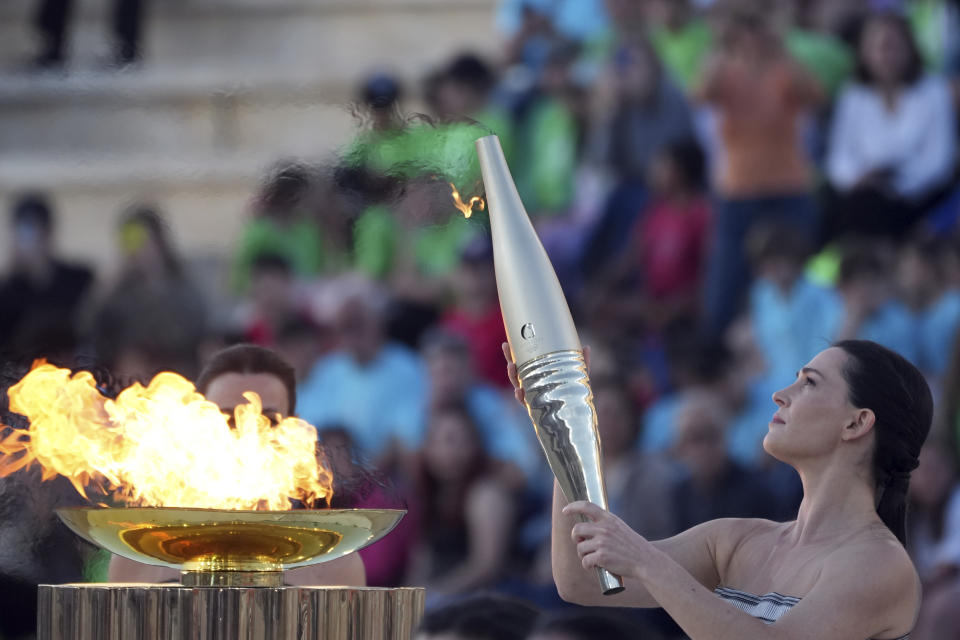 Actress Mary Mina, playing an ancient Greek high priestess, holds a torch with the Olympic Flame during the Olympic flame handover ceremony at Panathenaic stadium, where the first modern games were held in 1896, in Athens, Friday, April 26, 2024. On Saturday the flame will board the Belem, a French three-masted sailing ship, built in 1896, to be transported to France. (AP Photo/Petros Giannakouris)