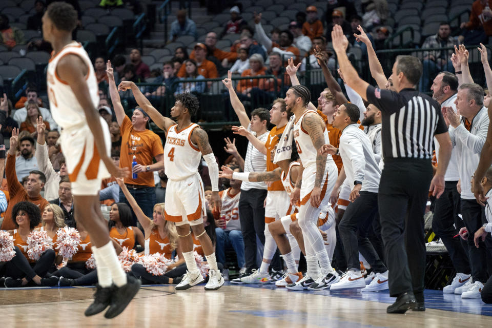 Texas guard Tyrese Hunter (4) and the Texas bench watch the flight of Hunter's 3-pointer during the second half of an NCAA college basketball game against Stanford, Sunday, Dec. 18, 2022, in Dallas. Texas won 72-62. (AP Photo/Jeffrey McWhorter)