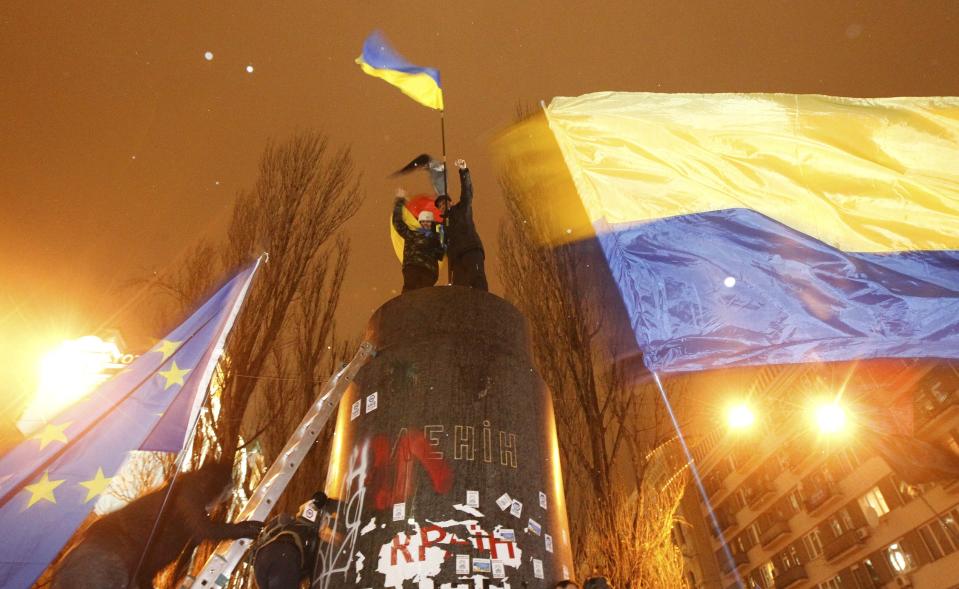 People climb up to the top of a pedestal after a statue of Soviet state founder Vladimir Lenin was toppled by protesters during a rally organized by supporters of EU integration in Kiev