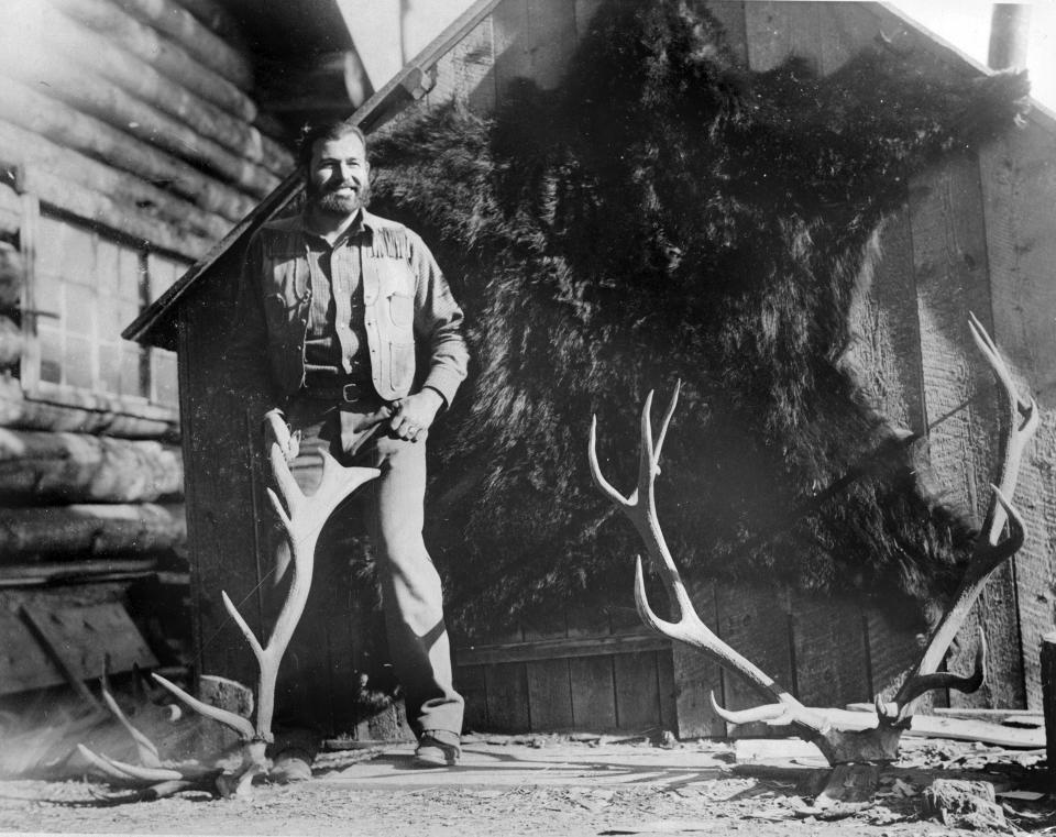 In this 1932 photo provided by the John F. Kennedy Library Foundation from the Ernest Hemingway Collection Ernest Hemingway posing with a bear skin and deer antlers during a hunting trip to Nordquist's Ranch in Wyoming. A new three-part documentary about Hemingway, which relied heavily on the archives at the John F. Kennedy Presidential Library and Museum in Boston, debuts April 5, 2021, on PBS. (John F. Kennedy Presidential Library and Museum, Boston via AP)