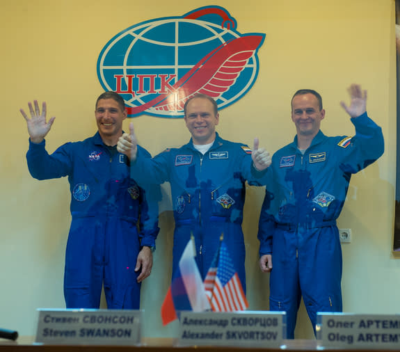 Expedition 37 NASA Flight Engineer Michael Hopkins, far left, Soyuz Commander Oleg Kotov and Russian Flight Engineer Sergey Ryazanskiy, far right, wave and give the thumbs up following a press conference held at the Cosmonaut Hotel, on Tuesday,