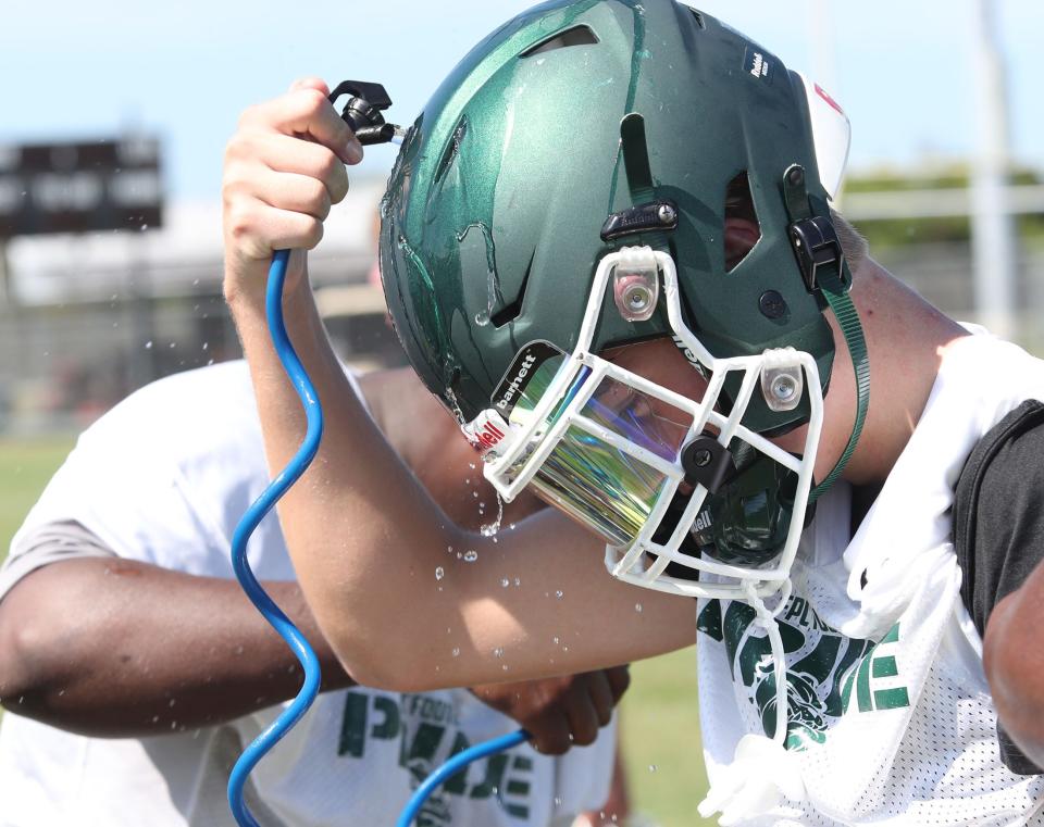 A Flagler Palm Coast player pours cold water into one of the vents in his helmet  on Aug. 1, 2022, during practice in Florida.