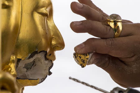 A craftsman fixes the statue of Hindu god Brahma after it was damaged during the deadly blast at the Erawan shrine in Bangkok, Thailand, August 26, 2015. REUTERS/Athit Perawongmetha