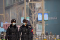 Security officers wearing face masks to prevent the spread of the coronavirus walk on patrol at a pedestrian shopping street in Beijing, Saturday, Jan. 23, 2021. (AP Photo/Mark Schiefelbein)