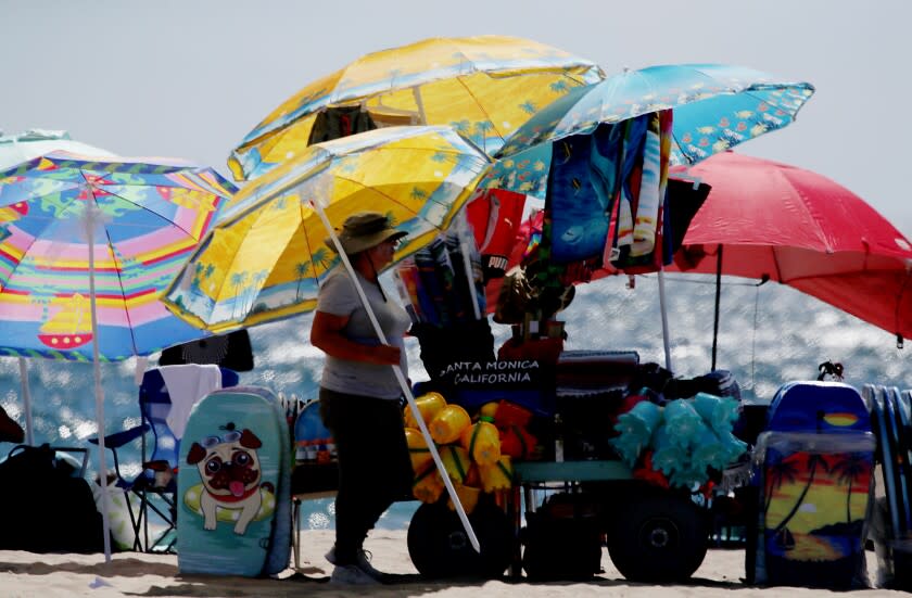 SANTA MONICA, CALIF. - AUG. 11, 2022.. A vendor selling umbrellas and assorted beach gear sets up shop on Santa Monica Beach.. (Luis Sinco / Los Angeles Timesd)