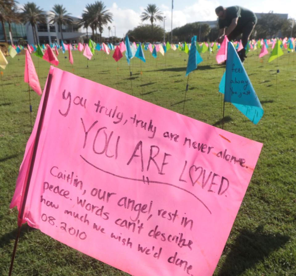 A student adds another flag to the many messages on small brightly colored flags covering the quad, Tuesday September 12, 2023 as Embry-Riddle Aeronautical University hosts the 10th annual Field of Hope, a suicide awareness event