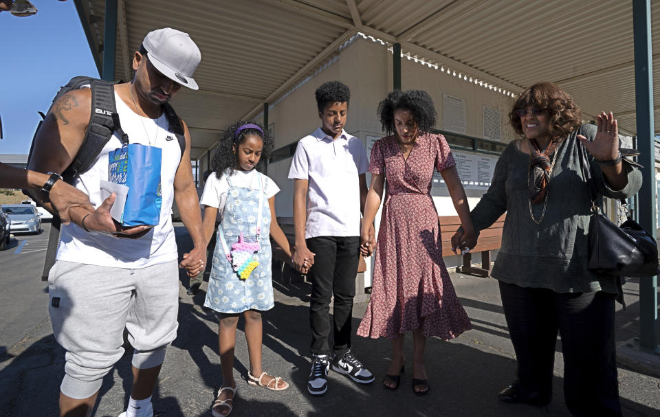 Gerald Massey, left, bows his head in prayer with this family, daughter Grace, 9, second from left, son Brian, 12, third from left, wife Jacq'lene, fourth from left, and mother-in-law, Grace Livngston-Nunley, right, after his release from Folsom State Prison in Folsom, Calif., Monday, July 3, 2023. (AP Photo/Rich Pedroncelli)