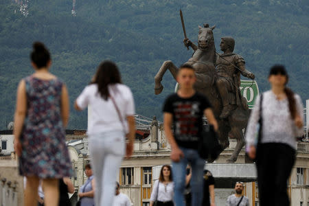 People walk in front of the "warrior on a horse" monument in central Skopje, Macedonia, June 4, 2018. It is widely believed that the statue depicts Alexander the Great. REUTERS/Marko Djurica