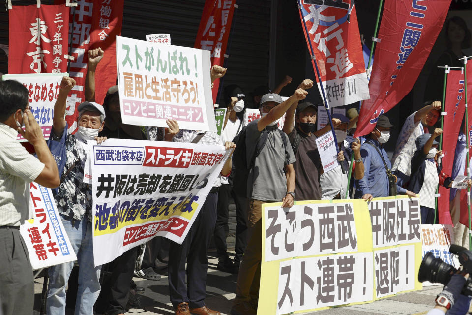 People who support a strike called by a union representing workers at Sogo & Seibu Co., shout slogans in front of the flagship Seibu Ikebukuro department store in Tokyo Thursday, Aug. 31, 2023. Labor union members of Japanese department store operator Sogo & Seibu stage a rare strike at its flagship store in Tokyo over job security concerns, as its parent company plans to sell the chain to a U.S. fund despite the union's opposition. The banners read "Sogo&Seibu, Strike solidarity, "bottom left, and "President Isaka, Resignation!, " bottom right. (Kyodo News via AP)