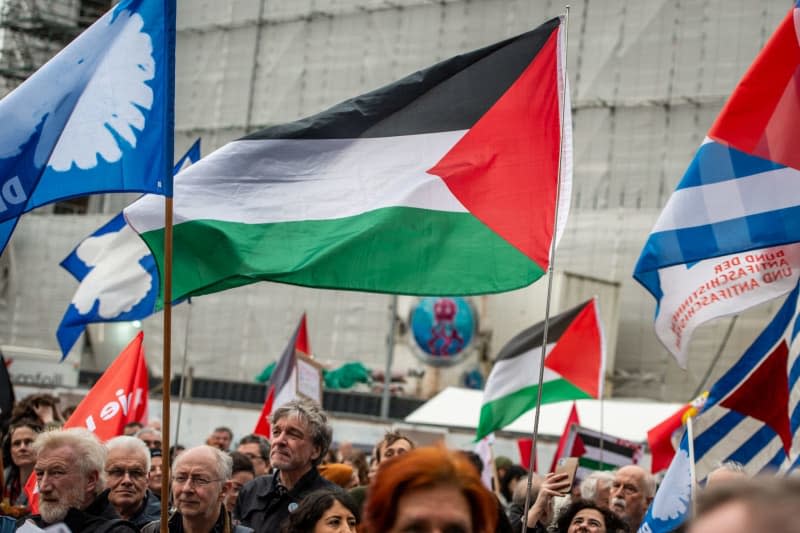 Des personnes tenant des drapeaux palestiniens et des drapeaux avec des colombes de la paix se rassemblent sur la Roncalliplatz pour la marche de Pâques sous la devise "Pour un redressement civil – mettez fin aux guerres, arrêtez le réarmement !".  Christian Knieps/dpa