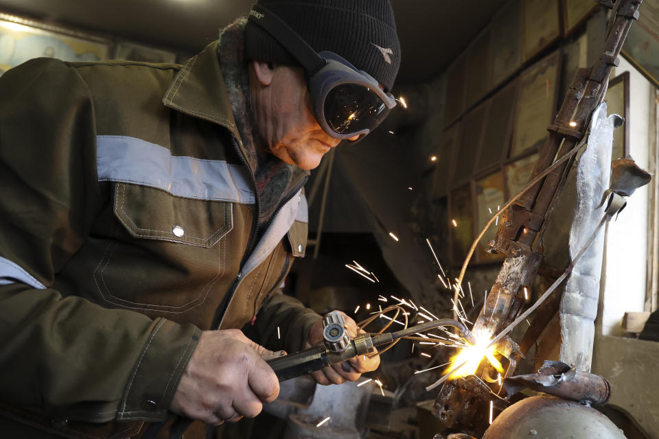 Viktor Mikhalev works in a workshop in his house in Donetsk, Russian-controlled Donetsk region, eastern Ukraine, Tuesday, Jan. 24, 2023. Mikhalev is transforming weapons and ammunition into flowers of war. Mikhalev, trained as a welder, lives and works in a house whose fence and door are decorated with forged flowers and grapes. (AP Photo/Alexei Alexandrov)