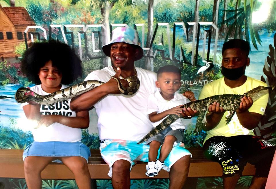 Thomas Gooch, wearing a hat, has some fun with a snake, an alligator and three of his kids at Gatorland in Orlando, Fla., in 2022. Left to right, Thomya, 10, Thomas, Torion, 3, Christian, 13