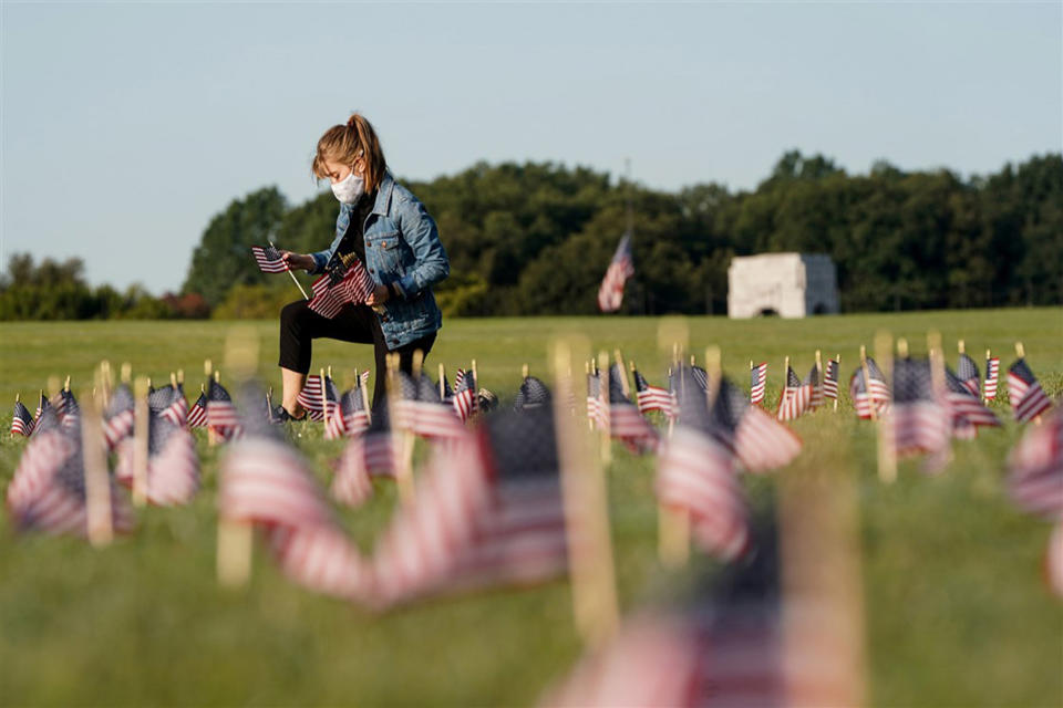 A volunteer places American flags representing some of the 200,000 lives lost in the United States in the coronavirus pandemic on the National Mall in Washington, on Sept. 22. (Joshua Roberts / Reuters)