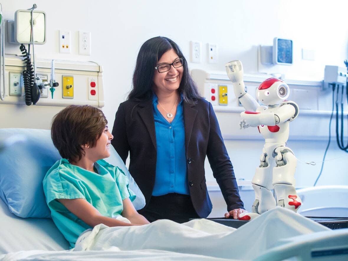 Dr. Samina Ali and her son Shaan with the MEDi robot. Ali, with the help of researchers in Canada and Scotland, is working on making the MEDi robot more socially responsive to better respond to children in pain.  (Laughing Dog Photography - image credit)