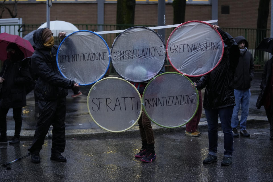 Activists of the C.I.O Comitato Insostenibili Olimpiadi (Unsustainable Olympics Commetee) hold signs in Italian reading: "Concreting, privatization, eviction" as they march in front of the building site of the 2026 Winter Olympic village in Milan, northern Italy, Saturday, Feb. 10, 2024, to protest the prospected costs of the 2026 Winter Olympics that will be disputed in Milan and Cortina d'Ampezzo in the Dolomites. (AP Photo/Luca Bruno)