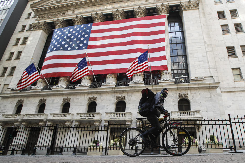 A delivery worker rides his electric bicycle past the New York Stock Exchange, Monday, March 16, 2020, in New York. New York leaders took a series of unprecedented steps Sunday to slow the spread of the coronavirus, including canceling schools and extinguishing most nightlife in New York City. (AP Photo/John Minchillo)