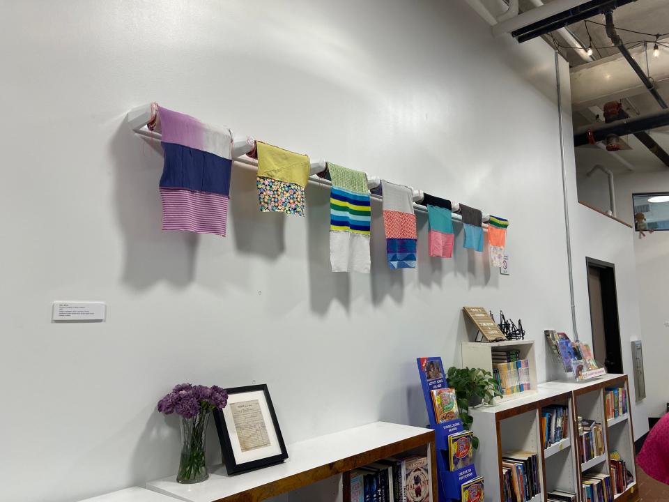 Woven pieces by Mary Elkins, adjunct professor at the university, hang above bookshelves inside Bookish, part of The Bakery District.