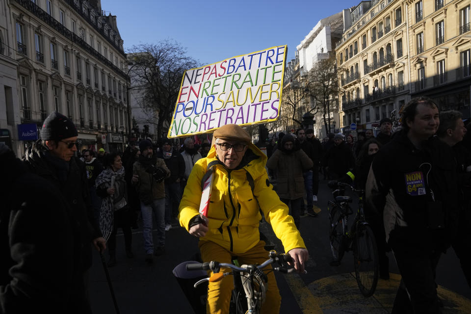 A protester rides bicycle with a poster reading "Not retreating to save our pensions" during a demonstration against plans to push back France's retirement age, Tuesday, Feb. 7, 2023 in Paris. The demonstration comes a day after French lawmakers began debating a pension bill that would raise the minimum retirement from 62 to 64. The bill is the flagship legislation of President Emmanuel Macron's second term. (AP Photo/Michel Euler)