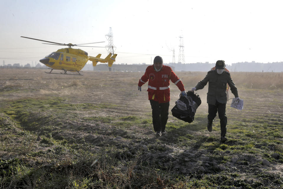 Rescue workers carry items retrieved from the scene where a Ukrainian plane crashed in Shahedshahr, southwest of the capital Tehran, Iran, Wednesday, Jan. 8, 2020. A Ukrainian airplane with more than 170 people crashed on Wednesday shortly after takeoff from Tehran's main airport, killing all onboard. (AP Photo/Ebrahim Noroozi)