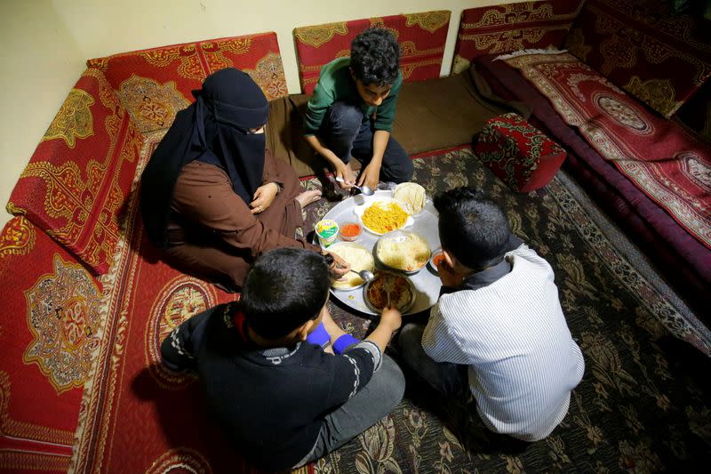 Mona Muhammad and her sons sit for a meal at their house in Sanaa