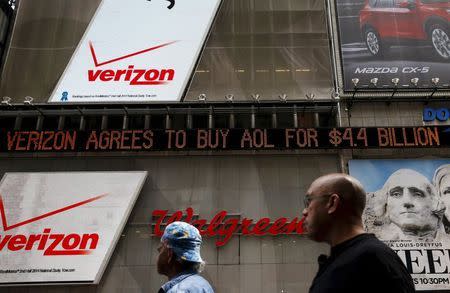 People walk by the Dow Jones electronic ticker at Times Square in New York in this May 12, 2015 file photo. REUTERS/Shannon Stapleton/Files