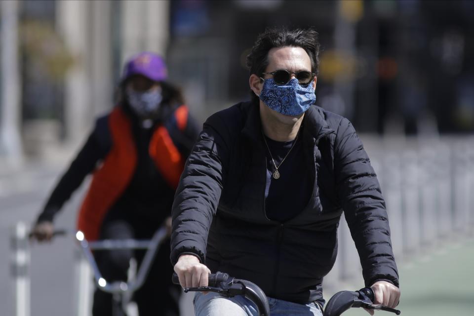 Cyclists wear protective masks as they pass Madison Square Park, Tuesday, May 12, 2020, in New York. (AP Photo/Frank Franklin II)