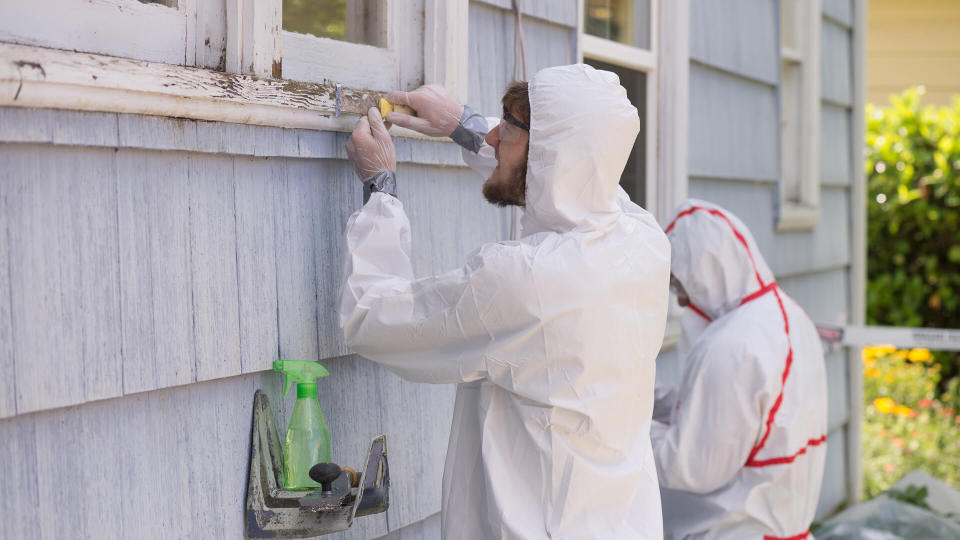 hazmat suit workers scrape off paint