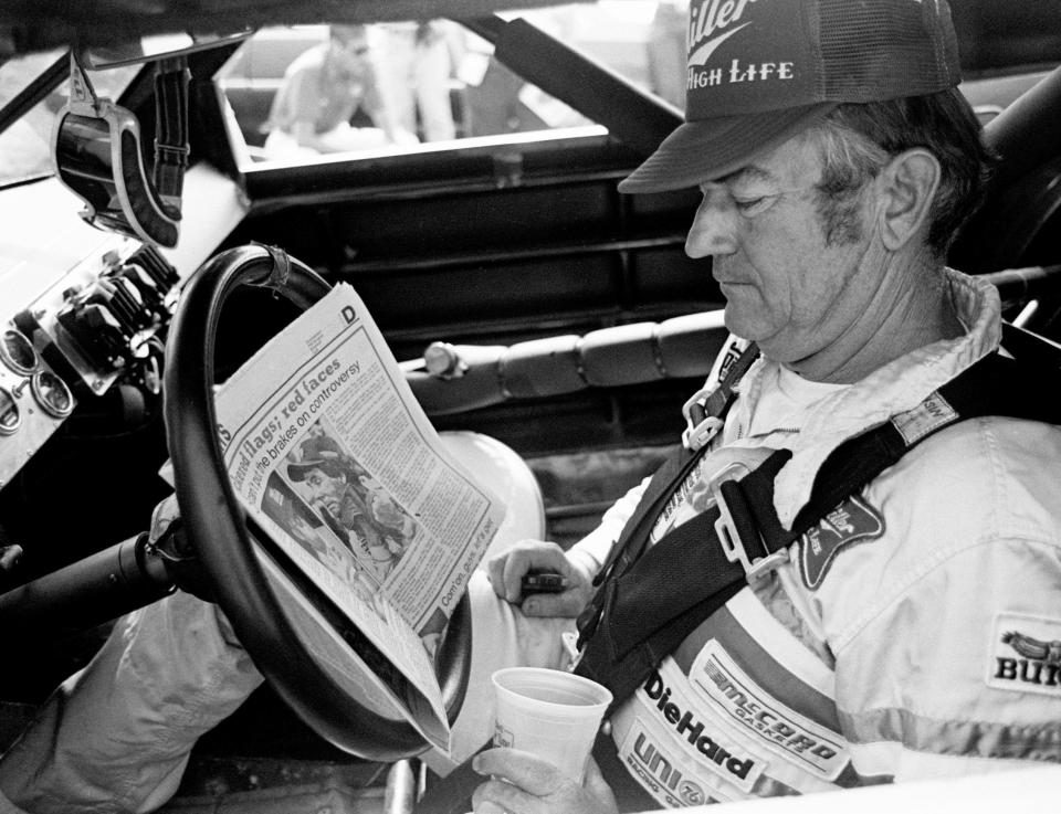 The defending Winston Cup points champion Bobby Allison checks out the newspaper before qualifying trials for the Nashville Pepsi 420 NASCAR Grand National race at Nashville International Raceway July 13, 1984.