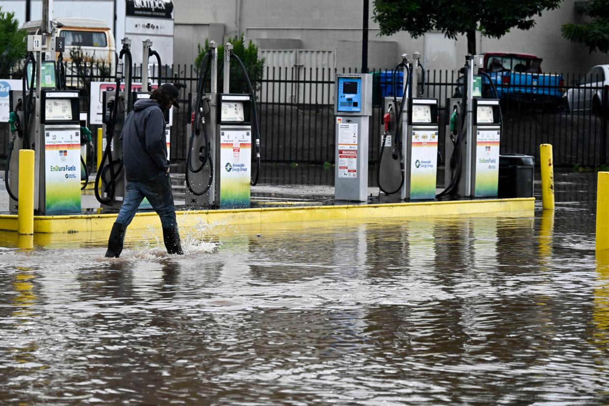 A gas station attendant walks past gas pumps on a flooded street, Tuesday, Feb. 6, 2024, in Lakeside, California