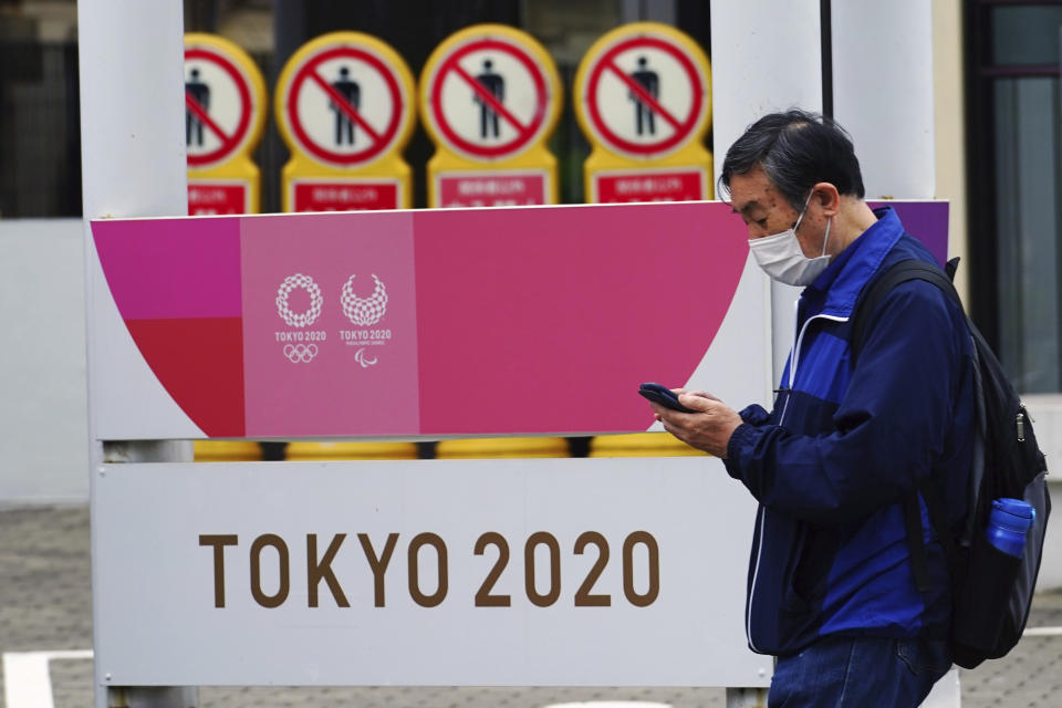 A man wearing a protective mask to help curb the spread of the coronavirus walks past a banner for the Tokyo 2020 Olympic and Paralympic Games in Tokyo Tuesday, May 11, 2021. The Japanese capital confirmed more than 920 new coronavirus cases on Tuesday. (AP Photo/Eugene Hoshiko)