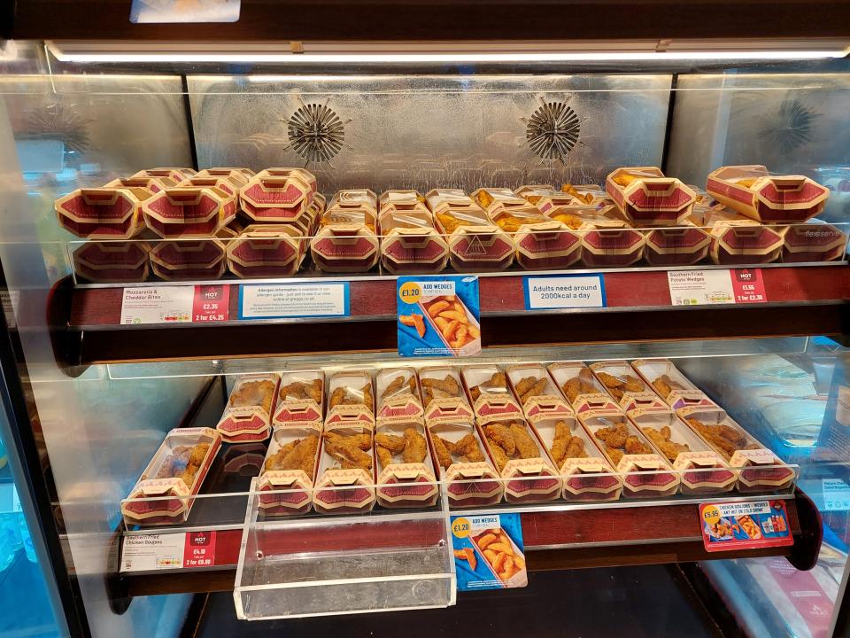 Hot food on offer at a Greggs store in London, including wedges, chicken goujons and cheese bites