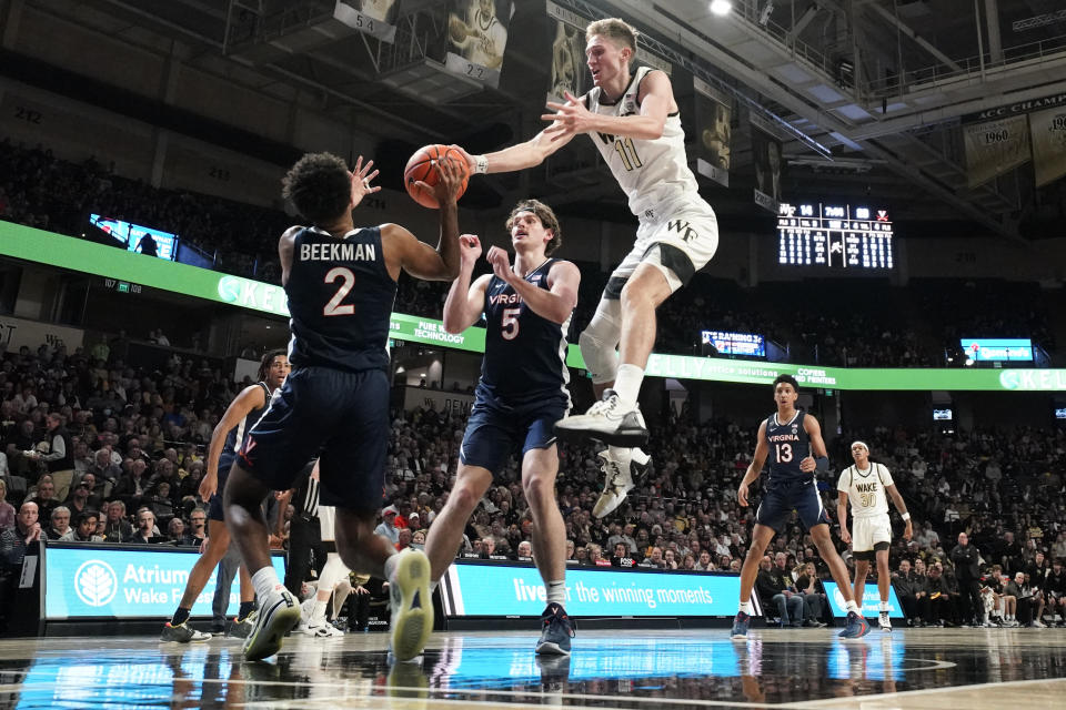Wake Forest forward Andrew Carr (11) loses the ball as he drives between Virginia guard Reece Beekman (2) and Ben Vander Plas (5) during the first half of an NCAA college basketball game in Winston-Salem, N.C., Saturday, Jan. 21, 2023. (AP Photo/Chuck Burton)
