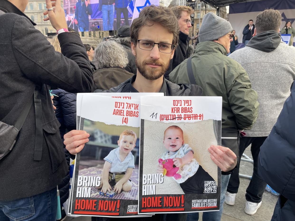 Eylon Keshet holding a photo of his cousin's children who were taken hostage alongside their parents on October 7