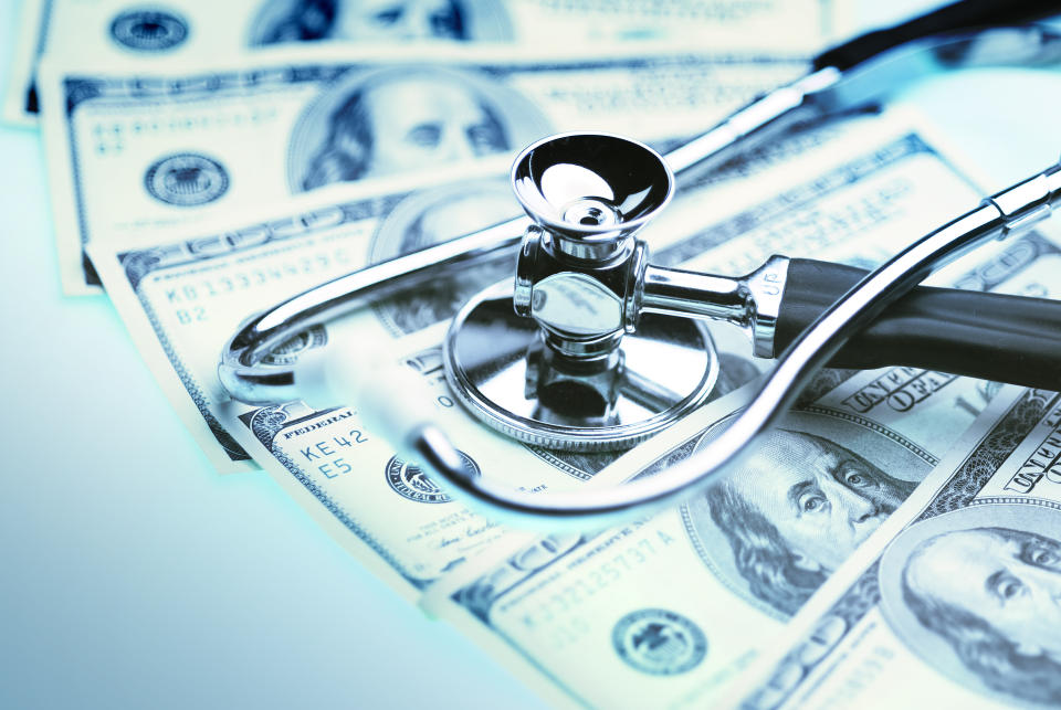 A stethoscope lies on top of fanned-out hundred-dollar bills.